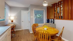 Eine kleine Küche mit Esstisch, Stühlen, Deckenventilator und einem Fenster mit Jalousien.