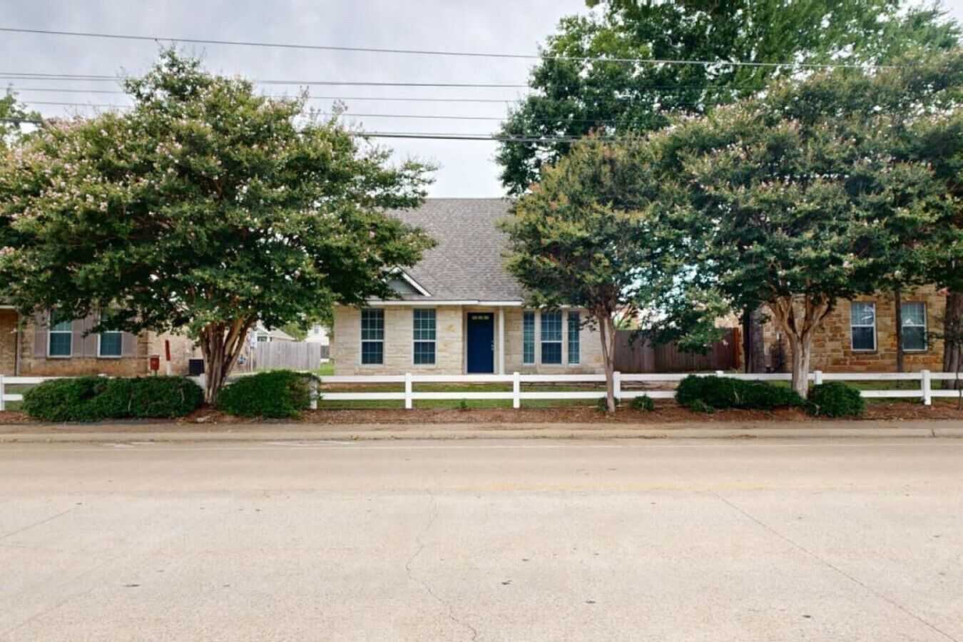 A two-story house with a white picket fence, a front door, and a garage.
