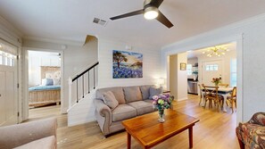 A spacious living room with a sofa, coffee table, and a painting on the wall. - Central Cottage Charm - Pet Friendly! Very Clean! (College Station)