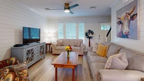 A living room with a television, two sofas, a coffee table, and a ceiling fan.
