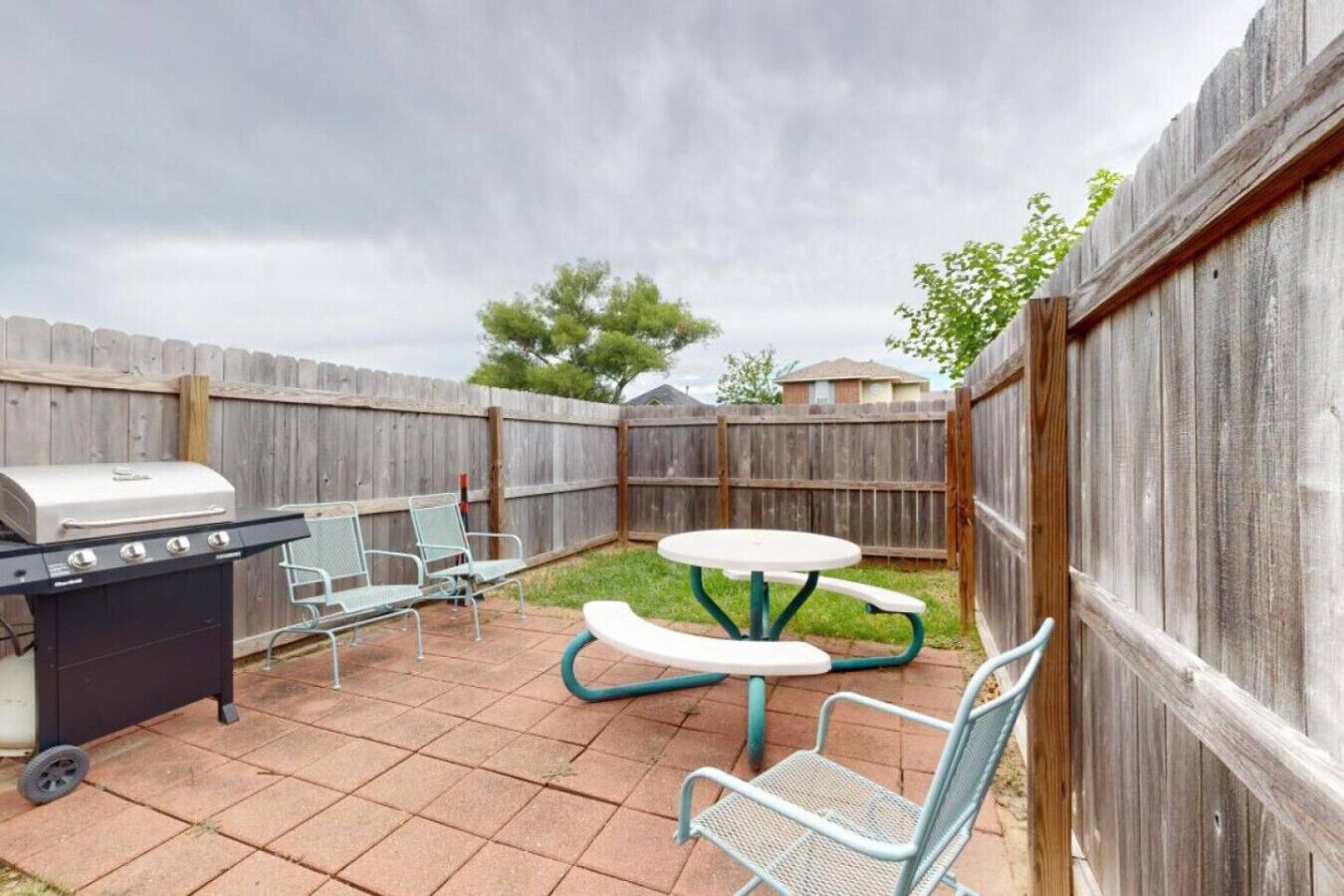 A backyard with a grill, a table, and chairs.