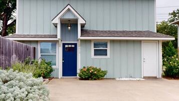 A two-story house with a blue front door, a small porch, and a garage.