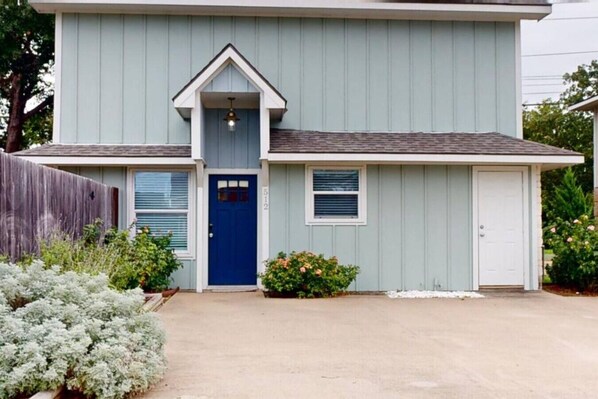 Ein zweistöckiges Haus mit blauer Haustür, einer kleinen Veranda und einer Garage.