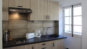 Eine moderne Küche mit Holzausbau, einer Edelstahl-Dunstabzugshaube, einer eingebauten Spüle und einem Fenster mit Blick.