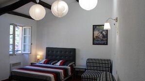 Ein Schlafzimmer mit einem Bett, einem Nachttisch, einem Sessel und einem Bild an der Wand.