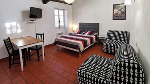 Ein Zimmer mit einem Bett, einem Tisch, zwei Stühlen, einem Sofa und einem Fernseher.
