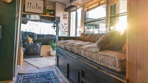 Un interior acogedor con una cama, una mesita, una planta en maceta y una ventana con vistas.