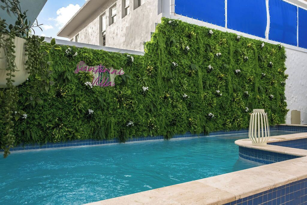 Zona de piscina con pared verde y un letrero que dice "Santorini Hotel".