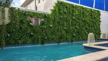 Zona de piscina con pared verde y un letrero que dice "Santorini Hotel".