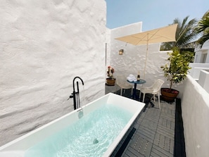 A spa area with a hot tub, outdoor seating, and a potted plant.