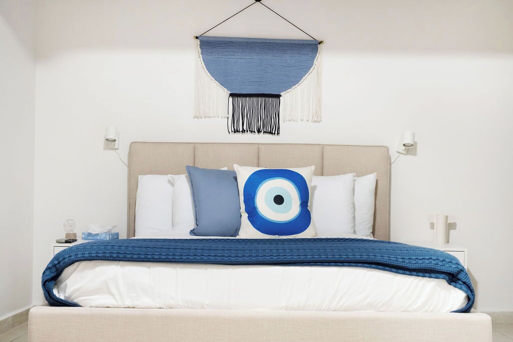 Un lit bien fait, avec une couverture bleue, une tête de lit et un élément décoratif bleu suspendu au-dessus.