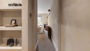 Un couloir étroit menant à une chambre qui contient un radiateur et un lit.