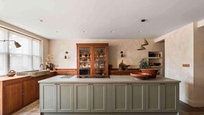Une cuisine spacieuse dotée d’un grand îlot central, de meubles en bois et d’un meuble intégré avec des portes en verre.