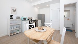 A modern kitchen with white cabinetry, a dining table with chairs, and a microwave. - Laughing Bird Suites (Governor's Harbour)