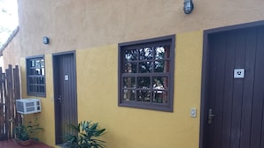 A building with a yellow exterior, a wooden fence, and a potted plant. - A Casa do Pablo (Buzios)