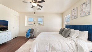 A bedroom with a bed, a ceiling fan, a TV, and two windows with blinds. - Near Strip & Airport - 3BR + Golf (Las Vegas)