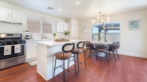 A modern kitchen with a central island, bar stools, and a dining area with a chandelier. - Near Strip & Airport - 3BR + Golf (Las Vegas)