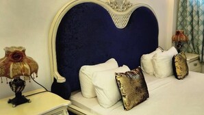 Un lit avec une tête de lit bleu foncé, du linge de lit blanc et des coussins décoratifs.