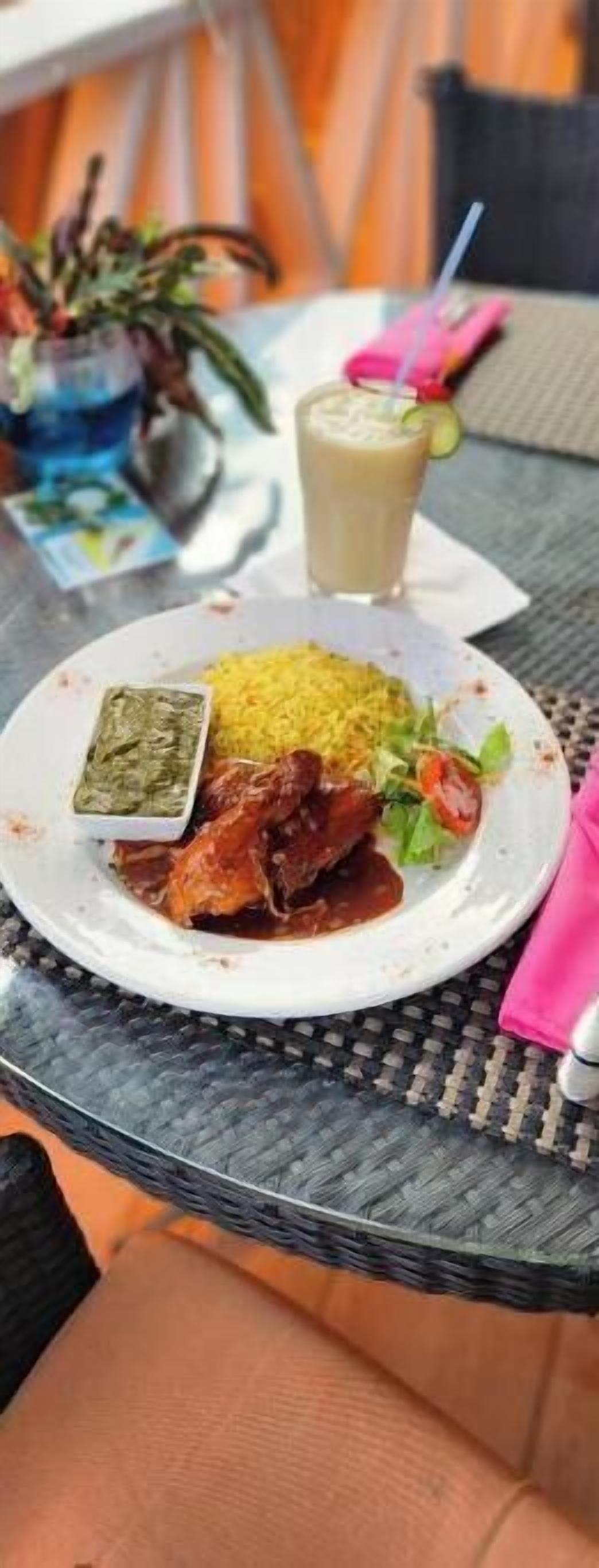 A meal with rice, a green sauce, a meat dish, and a salad on a white plate.