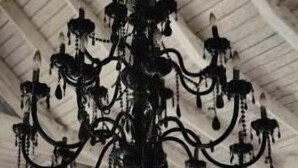 Un lustre suspendu à un plafond blanc, avec une rangée de fenêtres en dessous.