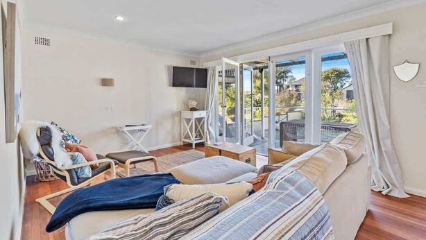 Una habitación con sofá, una silla, televisión y vistas al exterior.