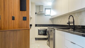 Eine moderne Küche mit Holzvertäfelung, einem Einbauofen, einem Geschirrspüler und einer schwarzen Arbeitsplatte.