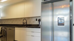 Eine moderne Küche mit Edelstahlgeräten, weißen Schränken und einer gemusterten Spritzschutzwand.