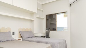 Ein Schlafzimmer mit zwei Betten, einem Schreibtisch und einem Fenster.