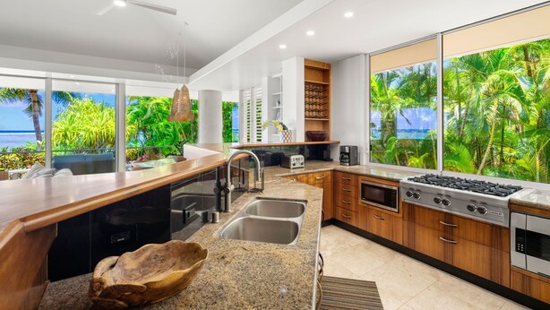 Una cocina moderna con una isla grande, electrodomésticos integrados y vistas a vegetación exuberante.
