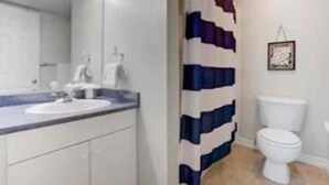 Une salle de bain avec un lavabo blanc, un miroir et des toilettes.