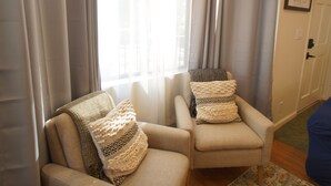 A room with two armchairs, one with a patterned throw and the other with a plain one.