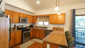 A modern kitchen with wooden cabinets, stainless steel appliances, and a granite countertop.