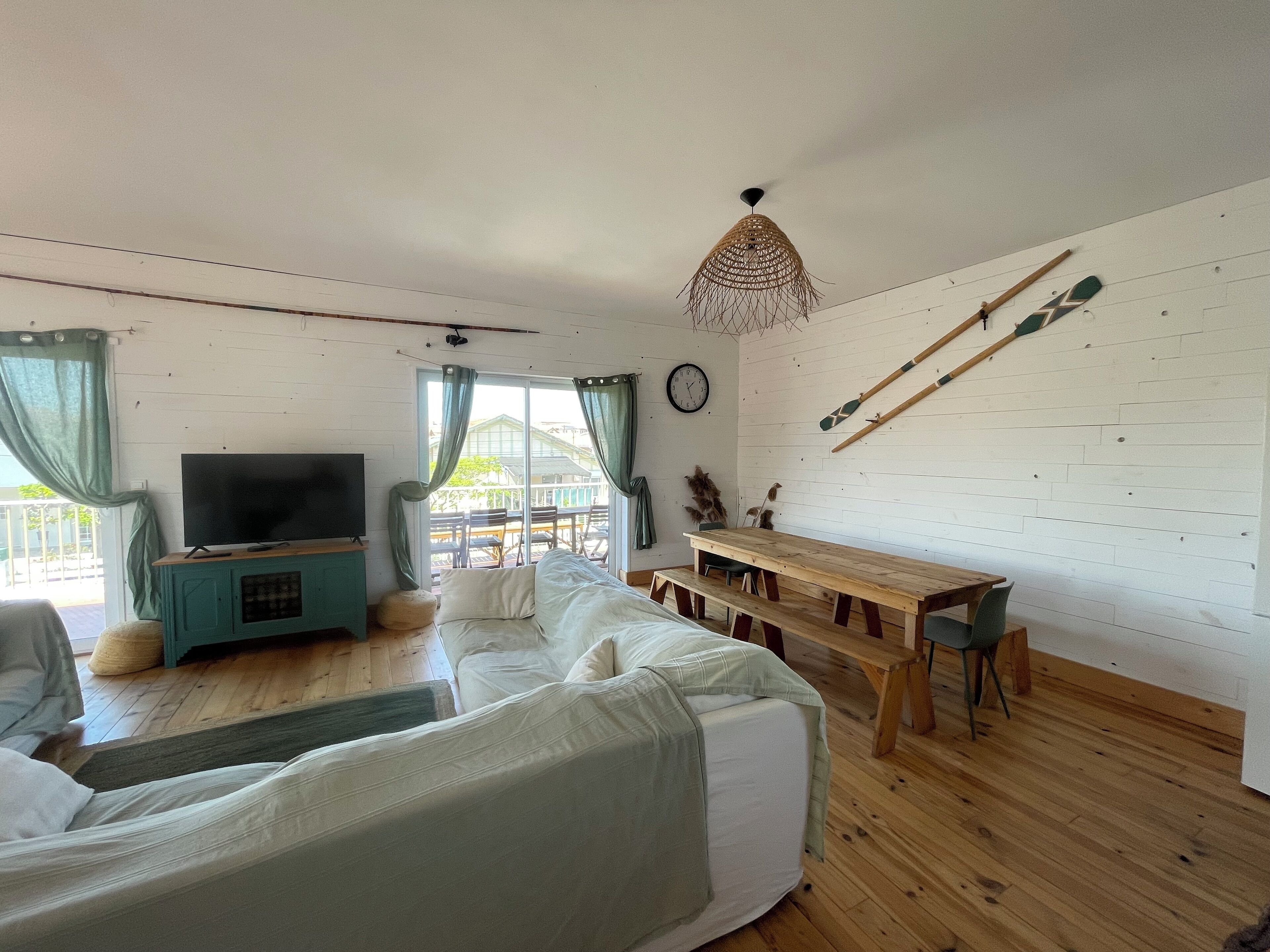 Ett mysigt vardagsrum med TV, soffa, ett matbord i trä och en takfläkt.