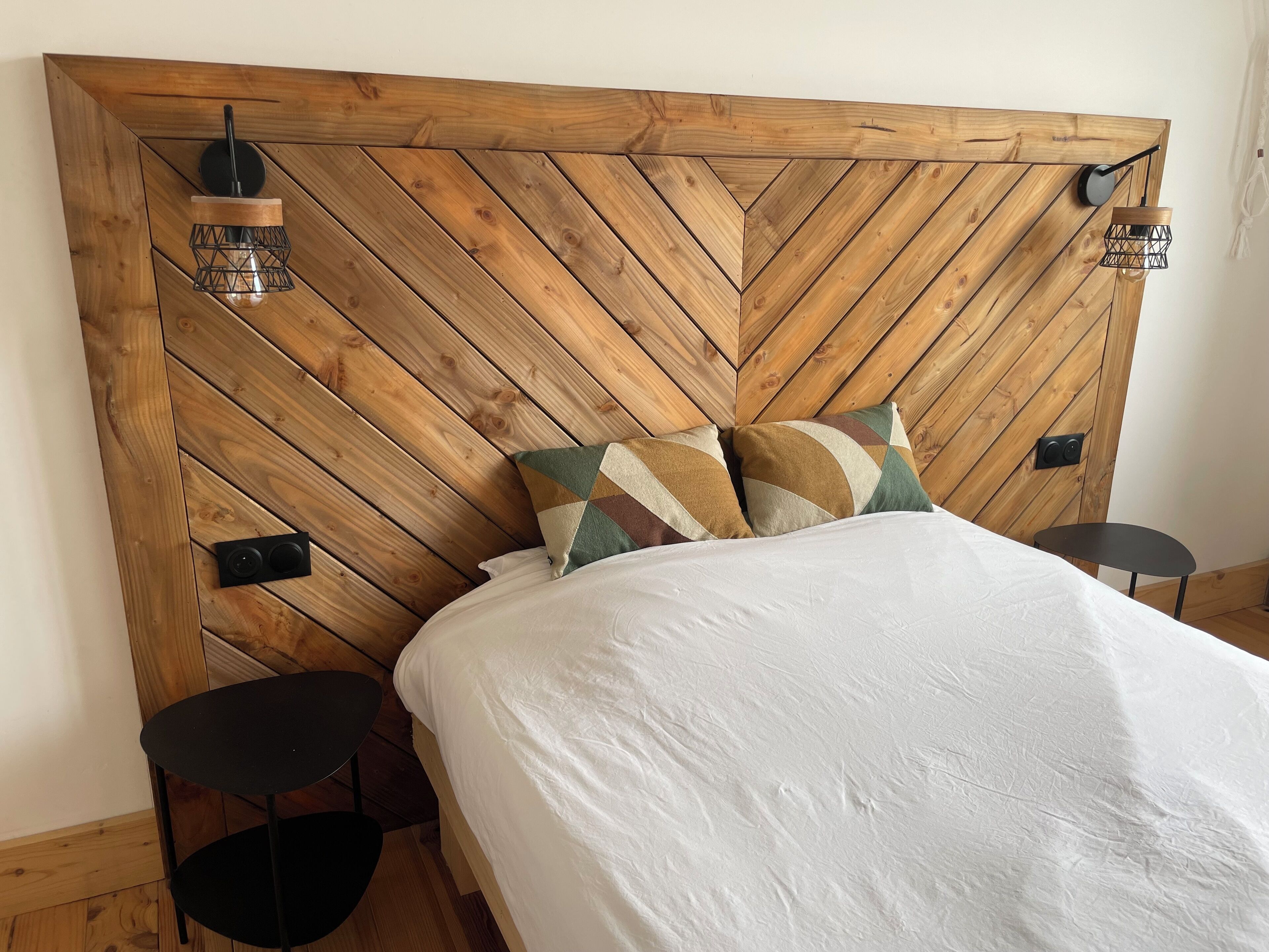 A bed with a wooden headboard, two black nightstands, and a white bedspread.
