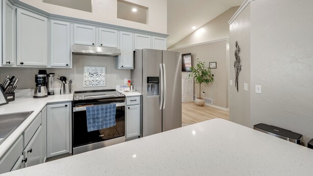 Una cocina moderna con armarios blancos, electrodomésticos de acero inoxidable y una isla central.