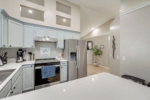 A modern kitchen with white cabinetry, stainless steel appliances, and a central island. - 1 Mi to Beach: Dog-Friendly Condo in Lake Mills! (Lake Mills)