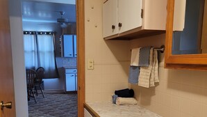 A kitchen with a sink, cabinets, and a door leading to a dining area. - Peaceful Nostalgic Farmhouse (Plankinton)