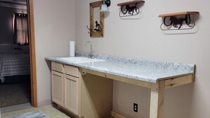 A bathroom with a wooden vanity, a sink, a mirror, and a towel rack. - Peaceful Nostalgic Farmhouse (Plankinton)