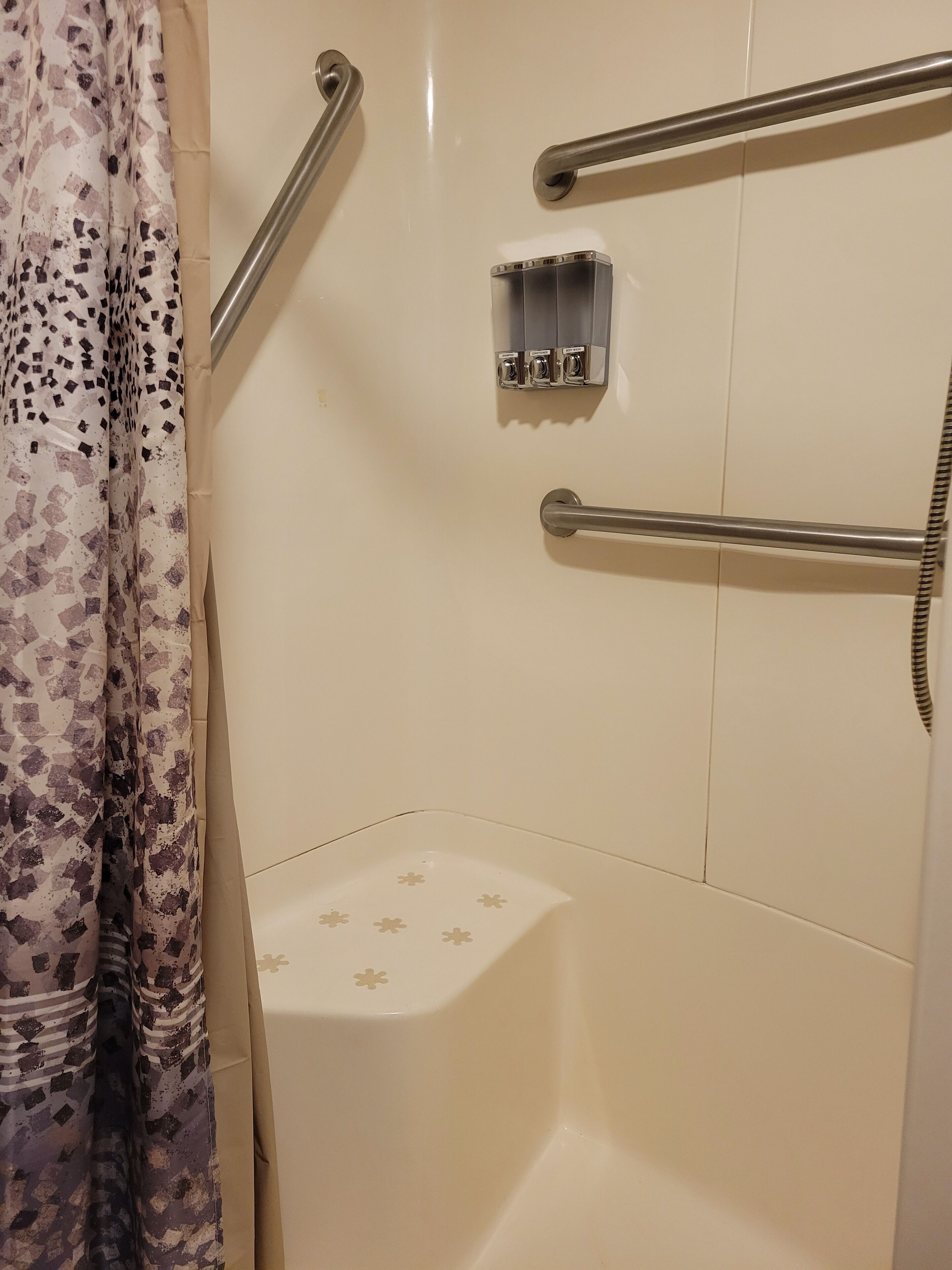 Kylpyhuone, jossa on suihkutila, wc ja tukikahva.