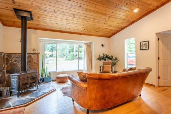 Una sala acogedora con chimenea de piedra, sofá de cuero y techo de madera.