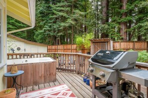 Una terraza con jacuzzi, parrilla y valla de madera.