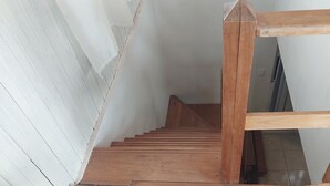 Una escalera de madera con paredes blancas y piso de baldosas.