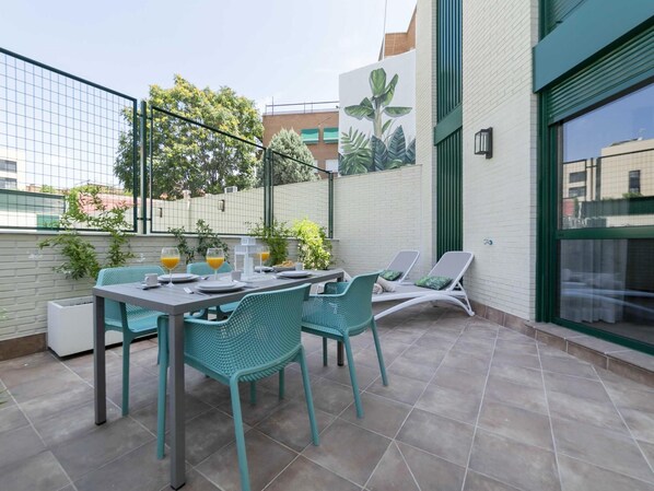 Un patio con una mesa preparada para dos, dos sillas y dos sillones.