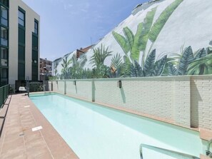 A swimming pool with a mural of tropical plants on the adjacent wall.