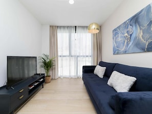 A modern living room with a sofa, TV, and artwork.