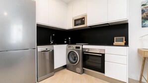 A compact kitchen with stainless steel appliances, a washing machine, and a microwave. - Aurora Stays by Charming IV, Apartment for 4 with free parking (Madrid)