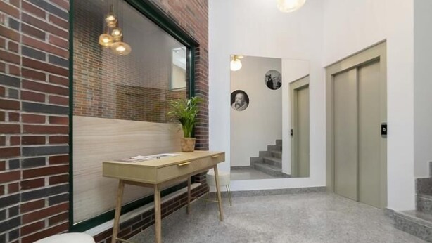 A modern interior with a brick wall, a wooden desk, a potted plant, and a staircase leading to another room. - Aurora Stays by Charming IV, Apartment for 4 with free parking (Madrid)