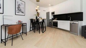 A modern kitchen with white cabinets, a black countertop, and a stainless steel dishwasher.