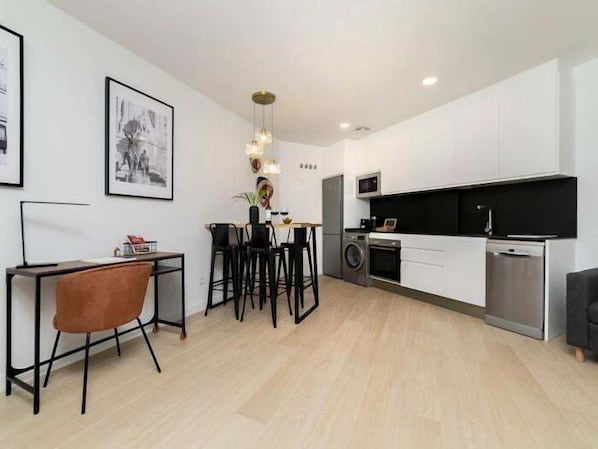 A modern kitchen with white cabinets, a black countertop, and a stainless steel dishwasher.