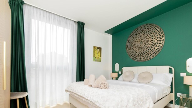 A bedroom with a bed, a chair, a lamp, and a wall decoration. - Aurora Stays by Charming VIII, Apartment for 4 with free parking (Madrid)